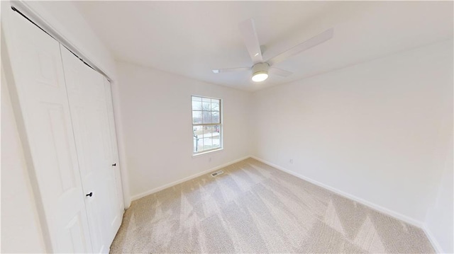 unfurnished bedroom with light colored carpet, ceiling fan, and a closet