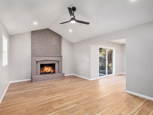 unfurnished living room with vaulted ceiling, ceiling fan, a fireplace, and light hardwood / wood-style floors