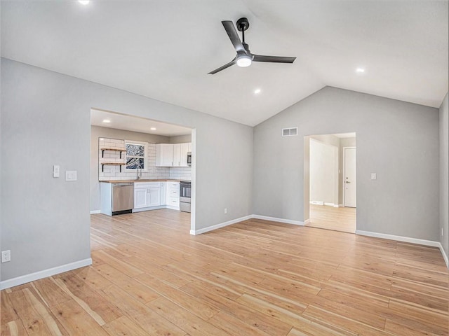 unfurnished living room with ceiling fan, lofted ceiling, sink, and light hardwood / wood-style flooring