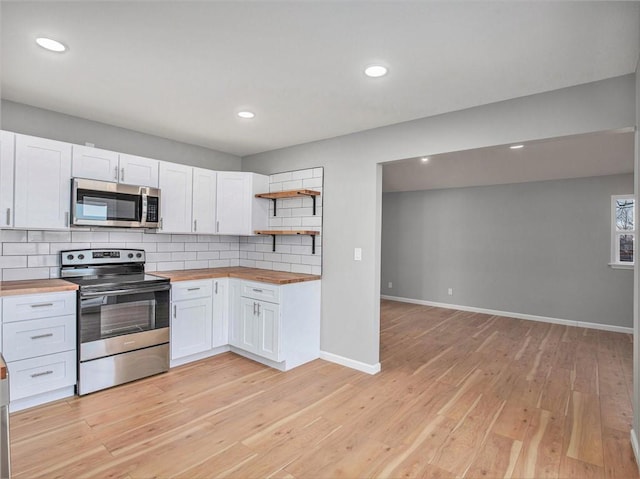 kitchen with wood counters, white cabinetry, tasteful backsplash, light wood-type flooring, and stainless steel appliances