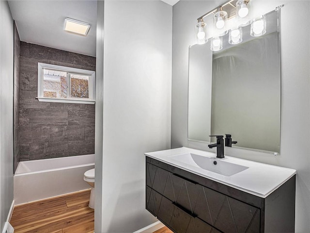 full bathroom featuring vanity, tiled shower / bath combo, wood-type flooring, and toilet