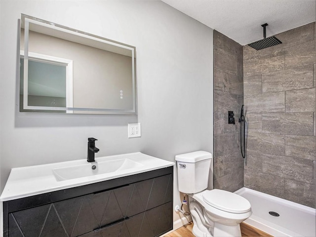 bathroom featuring vanity, toilet, wood-type flooring, and a tile shower