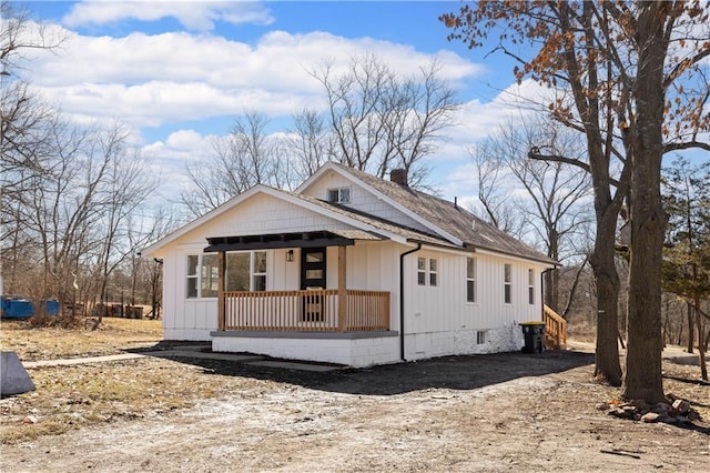 view of front of home featuring a porch, roof with shingles, and a chimney