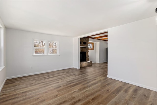 spare room with a fireplace, wood finished floors, and a wealth of natural light