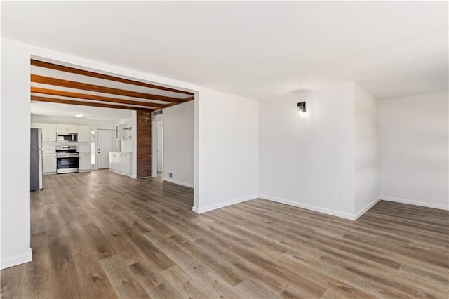 unfurnished living room with visible vents, baseboards, and wood finished floors