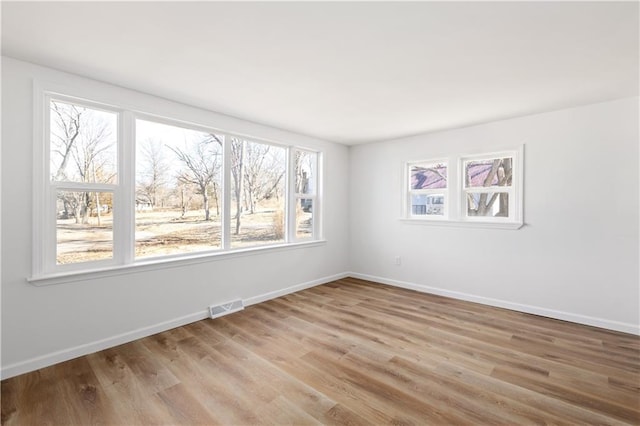 spare room with light wood-style floors, baseboards, and visible vents