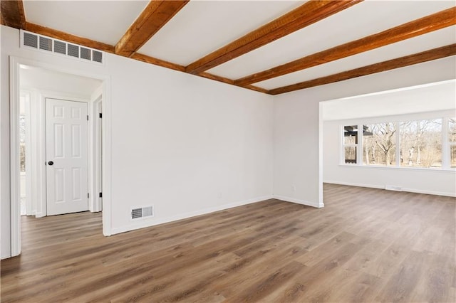 spare room featuring beam ceiling, wood finished floors, visible vents, and baseboards