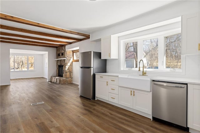 kitchen featuring appliances with stainless steel finishes, dark wood-type flooring, a sink, and white cabinets