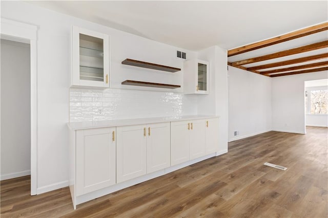 interior space with beam ceiling, visible vents, baseboards, and wood finished floors