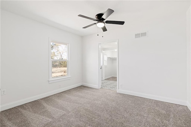 spare room featuring carpet floors, baseboards, visible vents, and ceiling fan