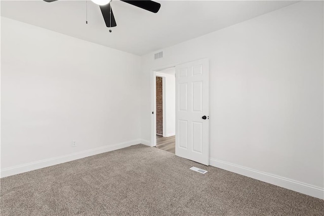 carpeted empty room featuring ceiling fan, visible vents, and baseboards