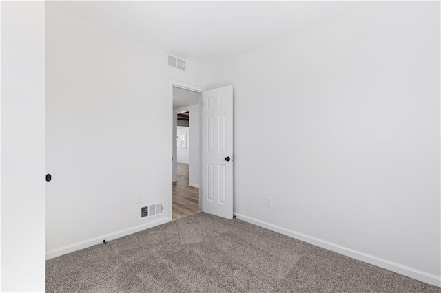 carpeted spare room with visible vents and baseboards