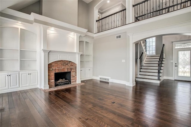 4300 SE Willow Ridge Dr, Blue Springs, MO 64014 - unfurnished living room featuring dark wood-type flooring, built in features, a brick fireplace, and a high ceiling