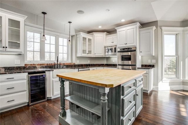 4300 SE Willow Ridge Dr, Blue Springs, MO 64014 - kitchen with appliances with stainless steel finishes, butcher block counters, hanging light fixtures, wine cooler, and white cabinets