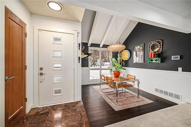 interior space with dark wood-style flooring, visible vents, a textured ceiling, and lofted ceiling with beams