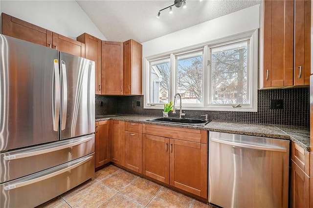 kitchen with lofted ceiling, stainless steel appliances, a sink, tasteful backsplash, and dark countertops