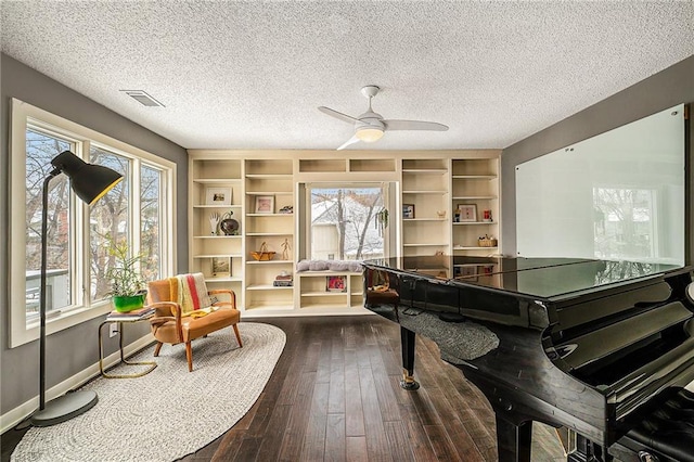 living area featuring dark wood-style flooring, visible vents, plenty of natural light, and baseboards