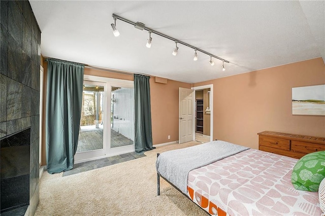 bedroom featuring access to exterior, a large fireplace, and light colored carpet