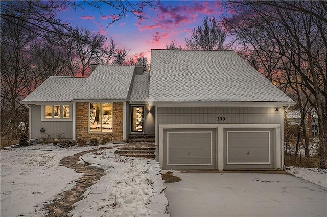 view of front of property with stone siding, roof with shingles, and an attached garage