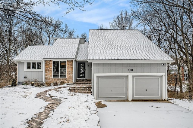 view of front of property featuring a garage, stone siding, a chimney, and roof with shingles