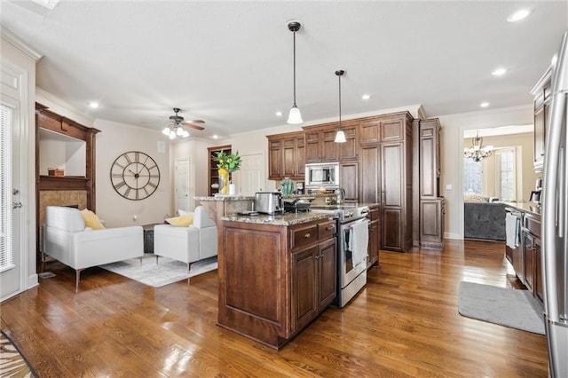 kitchen with light stone counters, pendant lighting, appliances with stainless steel finishes, open floor plan, and a kitchen island