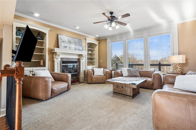 living room with a textured ceiling, built in shelves, ornamental molding, carpet, and a glass covered fireplace