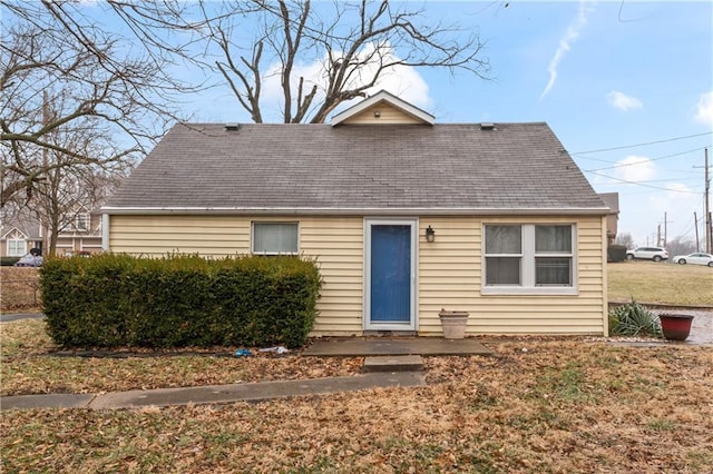 view of front of house with roof with shingles and a front yard
