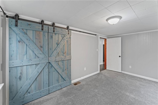 unfurnished room with a barn door and carpet floors