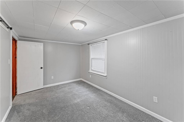 spare room featuring a barn door, ornamental molding, and carpet flooring