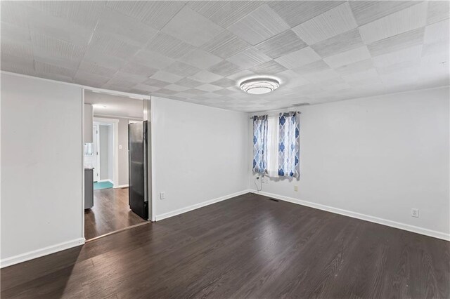 empty room with baseboards and dark wood finished floors