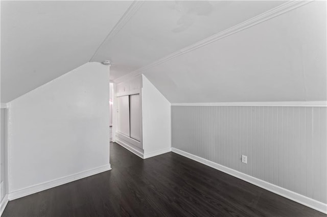 additional living space with baseboards, vaulted ceiling, and dark wood-style flooring