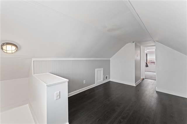 additional living space featuring baseboards, visible vents, dark wood finished floors, and lofted ceiling