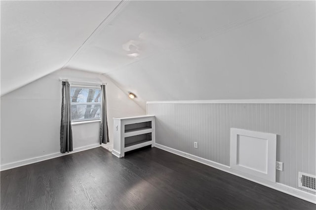 additional living space featuring vaulted ceiling, dark wood-style flooring, and visible vents