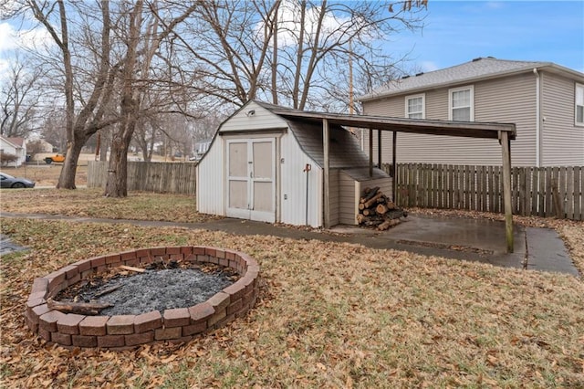 view of shed featuring fence and an outdoor fire pit