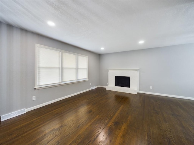 unfurnished living room featuring a fireplace and dark hardwood / wood-style floors