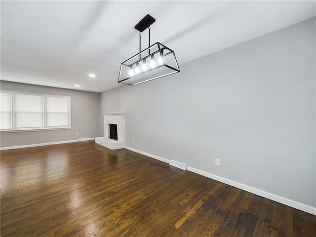 unfurnished living room featuring dark wood-type flooring and a fireplace