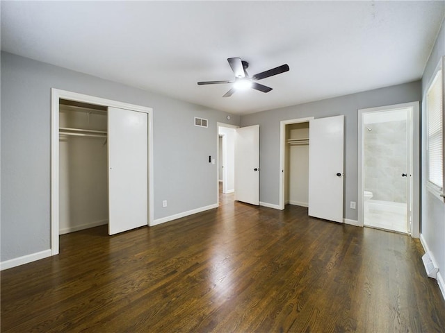 unfurnished bedroom featuring multiple closets, ceiling fan, dark wood-type flooring, and ensuite bath