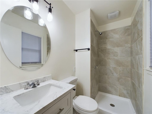 bathroom with vanity, a tile shower, and toilet