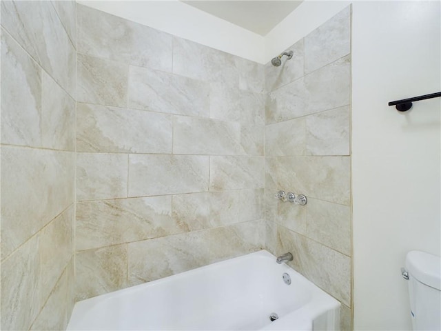 bathroom with tiled shower / bath combo and toilet