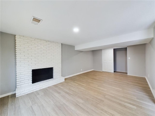 basement with a fireplace and light hardwood / wood-style flooring