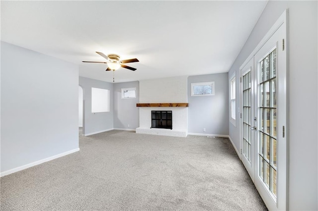 unfurnished living room featuring a brick fireplace, plenty of natural light, light carpet, and ceiling fan