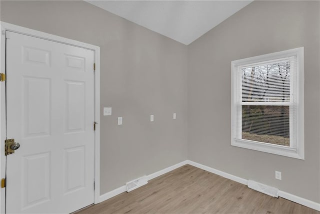 spare room featuring lofted ceiling and light hardwood / wood-style flooring