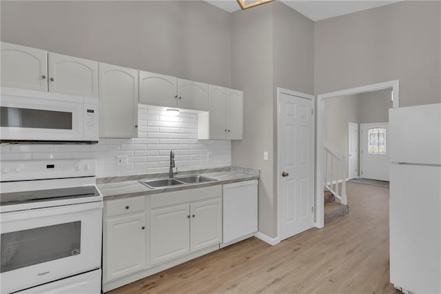 kitchen with sink, white cabinets, white appliances, and decorative backsplash