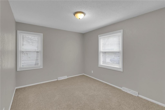 carpeted empty room featuring a textured ceiling