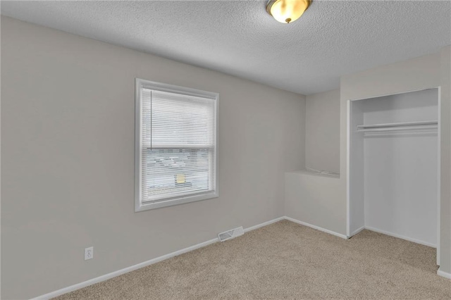 unfurnished bedroom with light colored carpet, a closet, and a textured ceiling