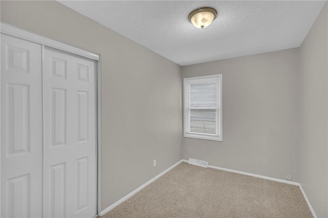 unfurnished bedroom featuring carpet, a textured ceiling, and a closet