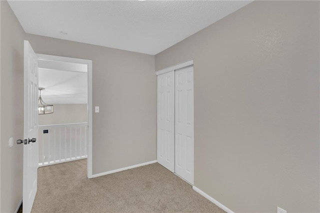 unfurnished bedroom featuring light carpet, an inviting chandelier, and a closet