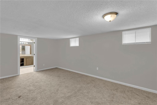 basement featuring light colored carpet and a textured ceiling