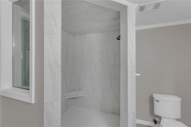 bathroom with ornamental molding, toilet, and a tile shower