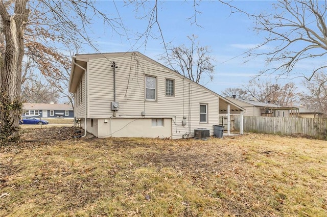 rear view of house with central AC and a yard